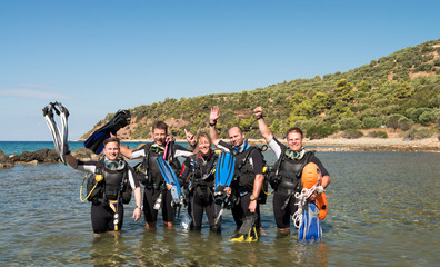 group of scuba divers standing on the shallow water of the sea shoreline denoting the social benefits of scuba diving