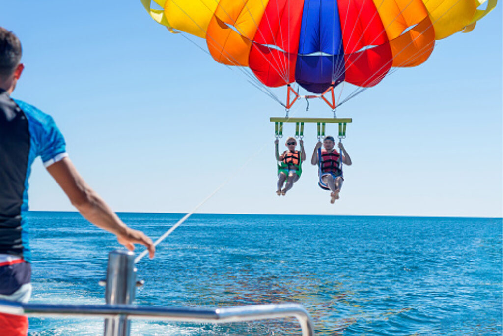 2 guests doing parasailing via speed boat in andaman sea. 