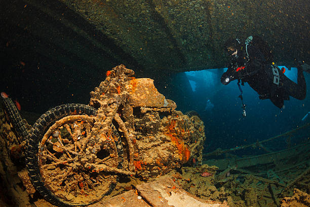 a scuba diver exploring the inner part of a shipwreck lying on the sea bed