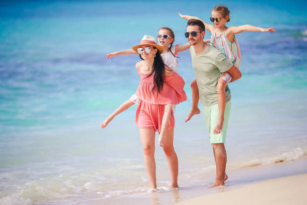 Young family of 4 members on beach vacation have a lot of fun together
